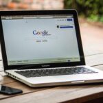 Ordinateur portable affichant la page d'accueil Google, posé sur table en bois