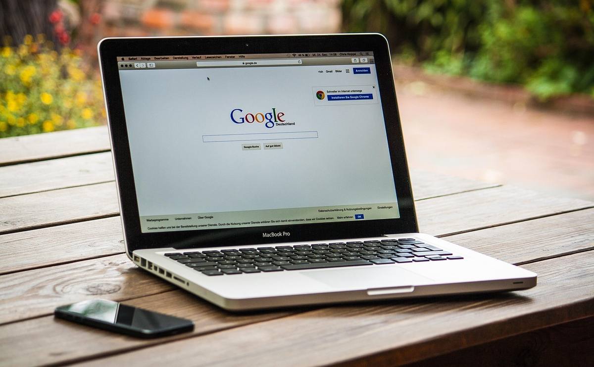 Ordinateur portable affichant la page d'accueil Google, posé sur table en bois