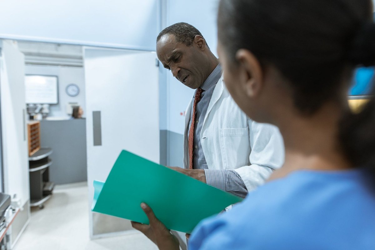 Médecin et infirmière en conversation dans un couloir hospitalier, tenant un dossier Médecin et infirmière en conversation dans un couloir hospitalier, tenant un dossier