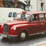 Taxi londonien rouge circulant en rue urbaine avec plaque de taxi éclairée