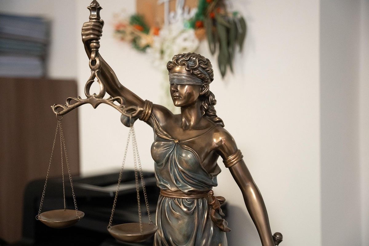 Statue dorée d'une figure aveugle tenant des balances dans un bureau Statue dorée d'une figure aveugle tenant des balances dans un bureau