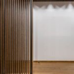 cloison en bois ajouré, mur blanc, sol en bois, plafond ajouré, espace vide