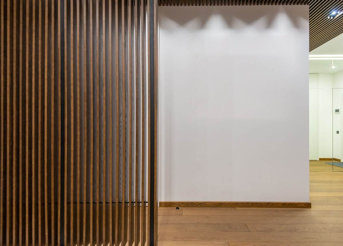 cloison en bois ajouré, mur blanc, sol en bois, plafond ajouré, espace vide