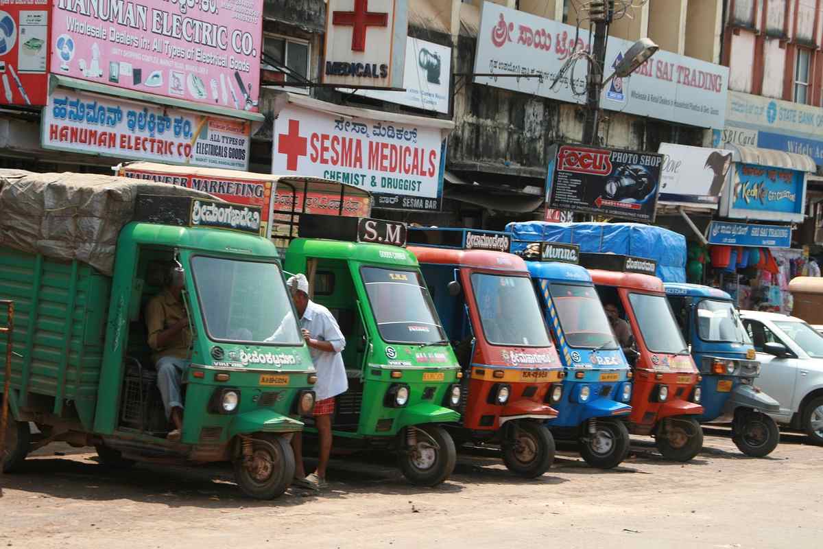 Des rickshaws colorés stationnés devant des boutiques et panneaux publicitaires
