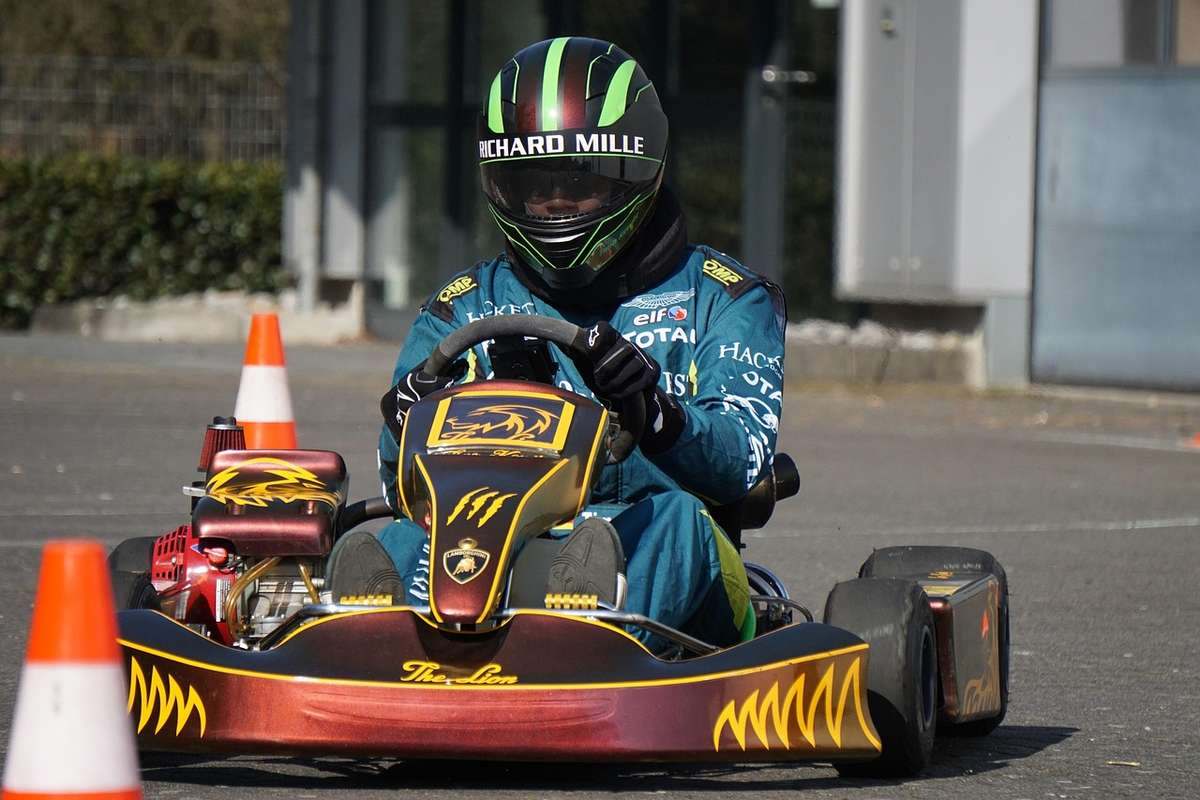 Pilote de kart en action sur circuit, portant un casque Richard Mille, entouré de cônes orange