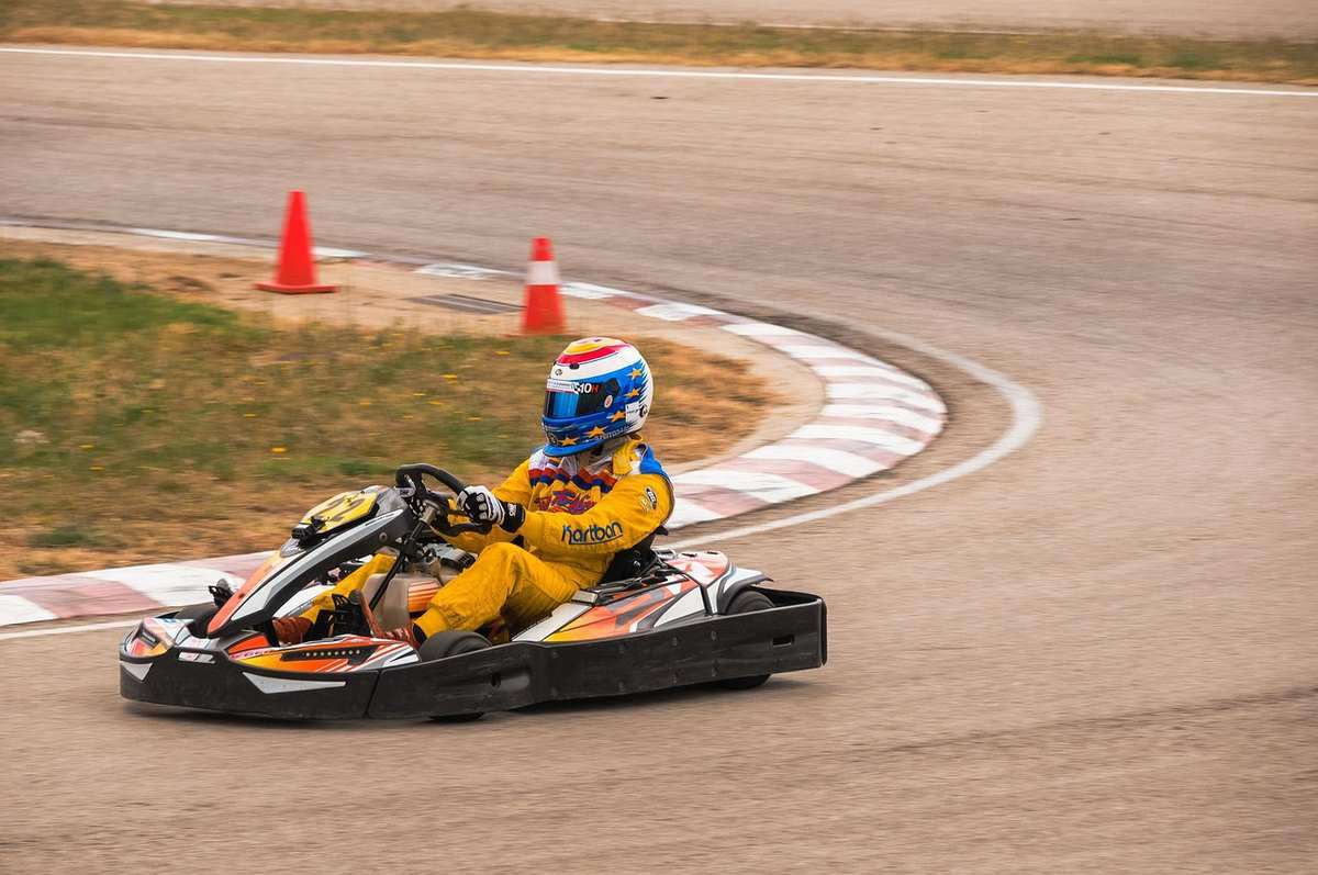 Pilote de kart en virage sur circuit, cônes de sécurité orange