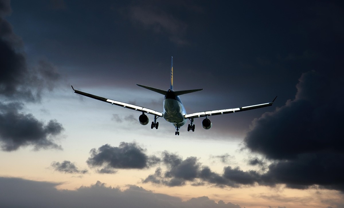 Avion décollant ou volant bas sous des nuages sombres, avec ses ailes et ses moteurs clairement visibles Avion décollant ou volant bas sous des nuages sombres, avec ses ailes et ses moteurs clairement visibles