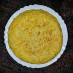 Tortilla espagnole dorée sur assiette blanche, plan de travail sombre