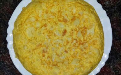 Tortilla espagnole dorée sur assiette blanche, plan de travail sombre