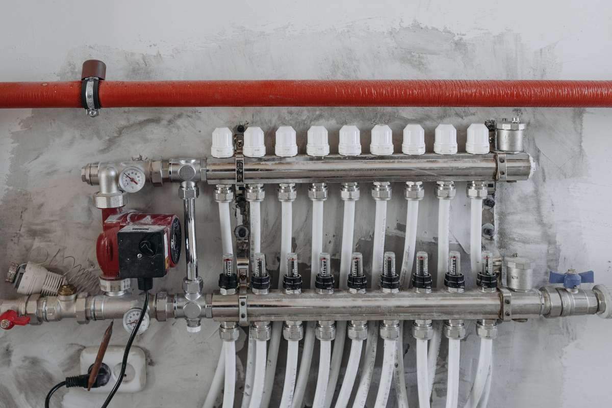 Manifold de chauffage avec tuyaux blancs, vanne et pompe sur mur