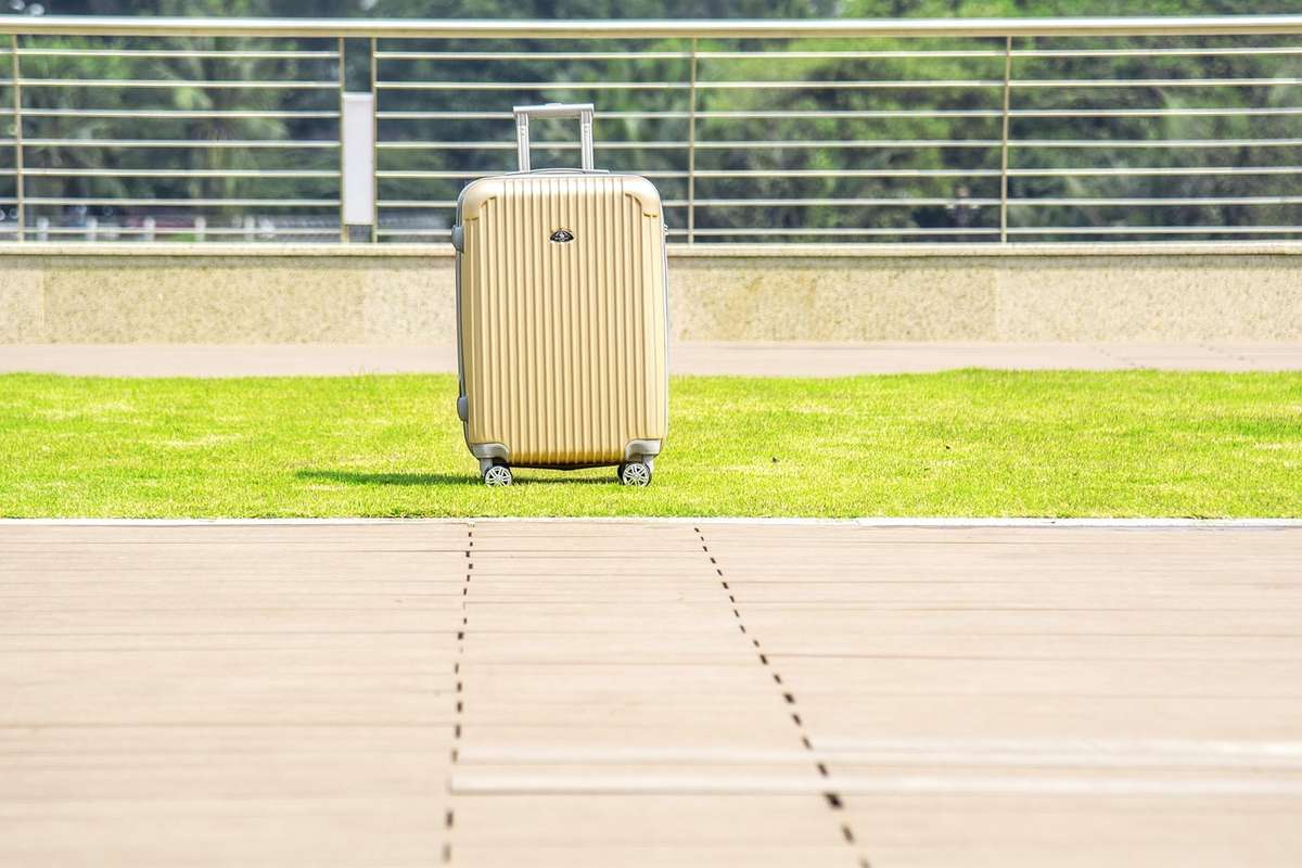 Un suitcase beige posé sur l'herbe à côté d'un trottoir
