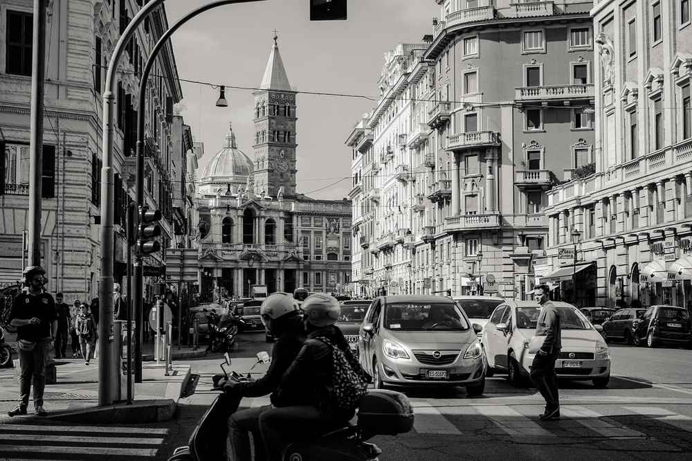Des piétons, véhicules et un scooter traversent une rue urbaine Des piétons, véhicules et un scooter traversent une rue urbaine