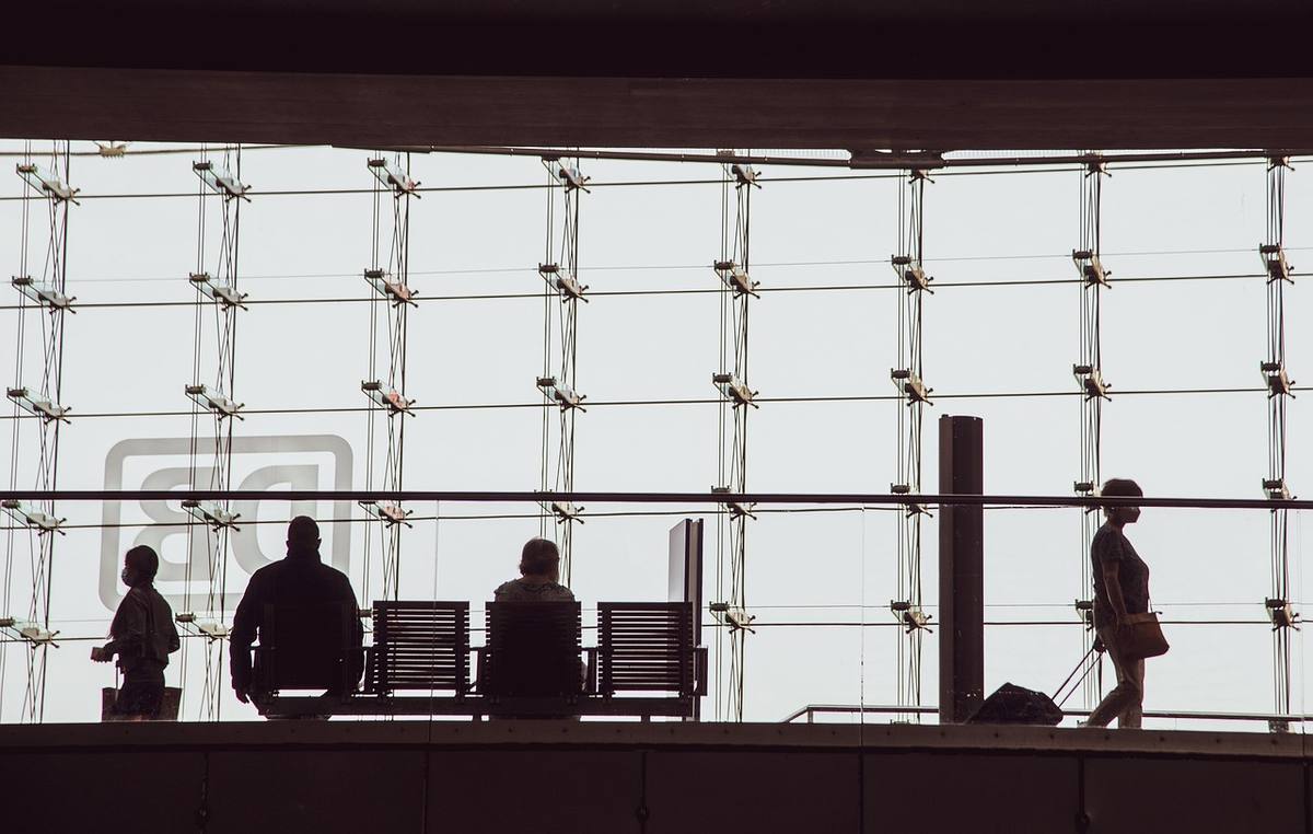 Silhouettes d voyageurs devant une grande vitre, chaises et bagages