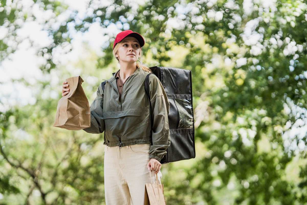 Femme portant sacs en papier et sac à dos dans un environnement forestier Femme portant sacs en papier et sac à dos dans un environnement forestier