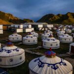 Yurtes traditionnelles disposées sur un terrain herbeux, collines en arrière-plan, crépuscule
