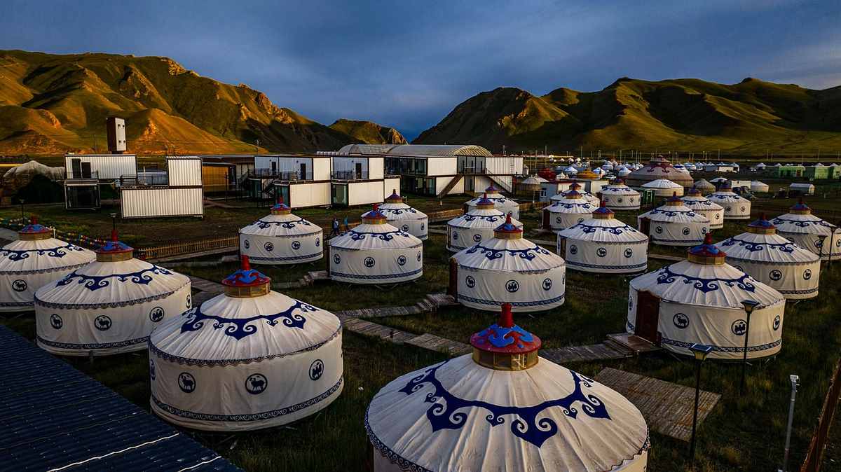 Yurtes traditionnelles disposées sur un terrain herbeux, collines en arrière-plan, crépuscule